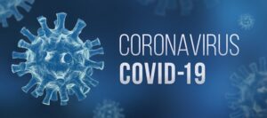 Illustration of the COVID-19 virus on a blue background with the text "CORONAVIRUS COVID-19" displayed prominently to the right. The virus is depicted as a spherical object with spike-like protrusions.