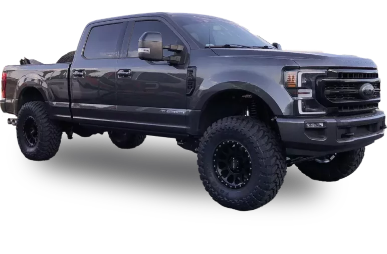 A lifted, dark gray Ford Super Duty pickup truck with large off-road tires and black wheels. The truck has a crew cab and a short bed, featuring a robust and rugged appearance with tinted windows and noticeable suspension modifications.