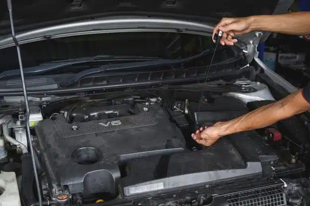 Fluid services in St. Cloud, FL at FloState Auto Diesel Repair. Image of an auto mechanic checking the CVT transmission fluid level on the oil dipstick, ensuring optimal fluid levels for smooth vehicle operation.