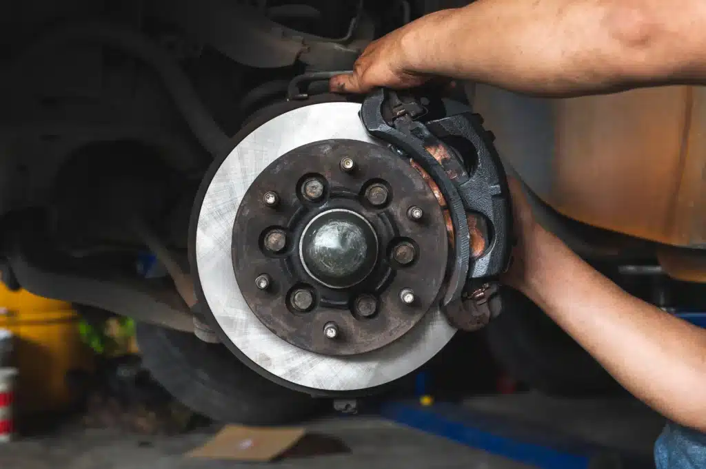 Ultimate Guide to Brake Repair and Services in St. Cloud, FL: Expert Insights from FloState Auto Diesel. Image showing a mechanic replacing brake pads and inspecting the rotor on a vehicle, highlighting FloState Auto Diesel's expertise in providing comprehensive brake maintenance and repair services.