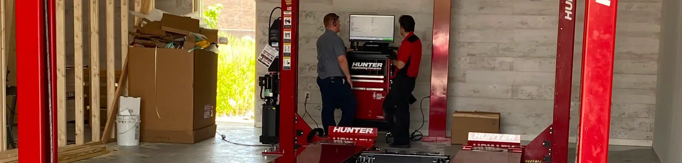 Wheel Alignment in St. Cloud, FL at FloState Auto Diesel Repair. Two technicians standing by a Hunter wheel alignment system, reviewing data on a computer screen.