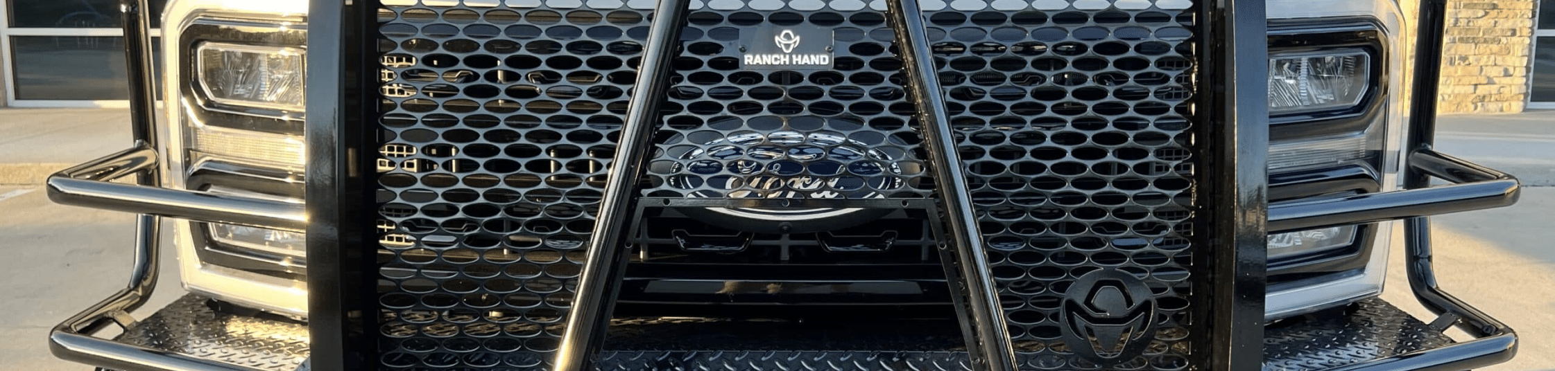 Close-up of a truck's front grille with a black metal guard and visible headlights.