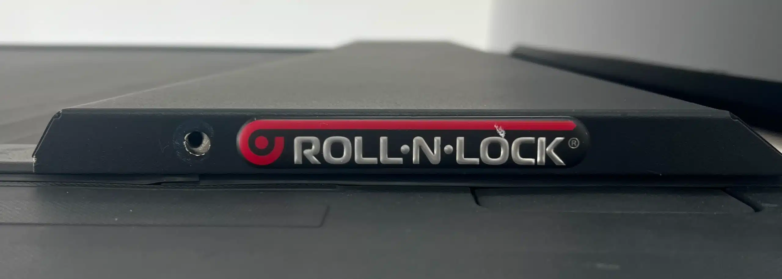 Close-up of Roll-N-Lock cover, a sleek accessory with a partially visible logo. The smooth surface hints it’s part of a vehicle system, complementing lift kits for trucks in St. Cloud FL with style and functionality.