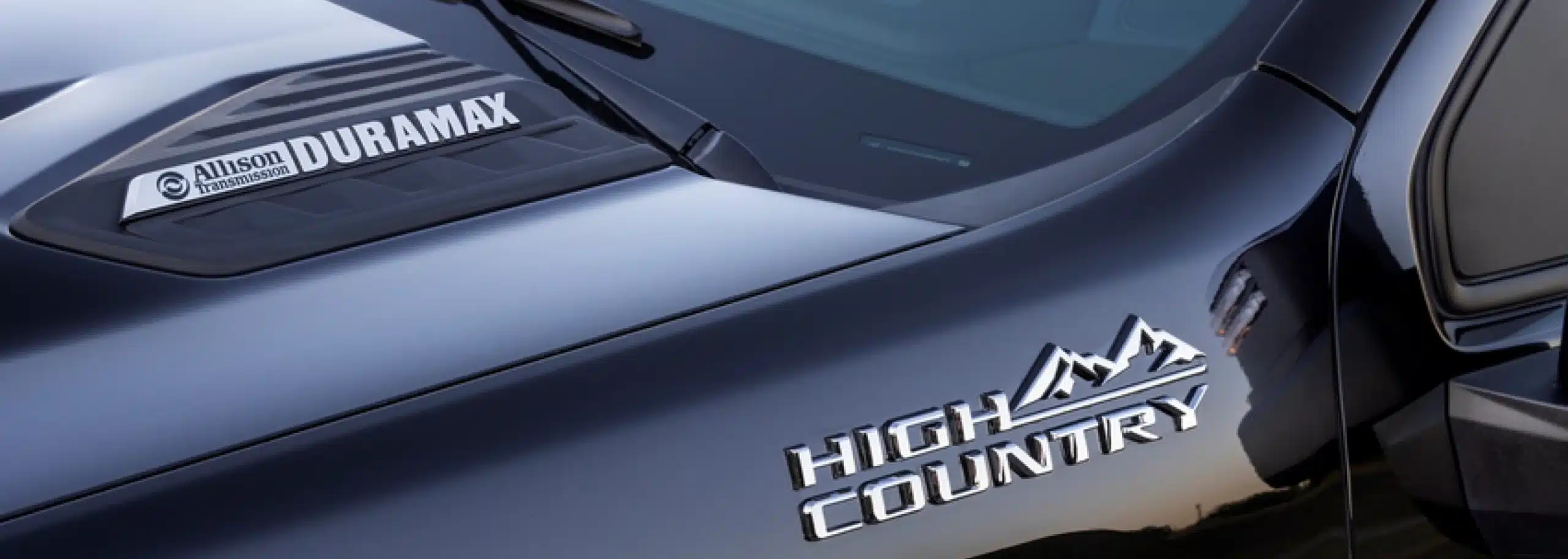 Close-up of a Duramax badge and High Country logo on a vehicle.