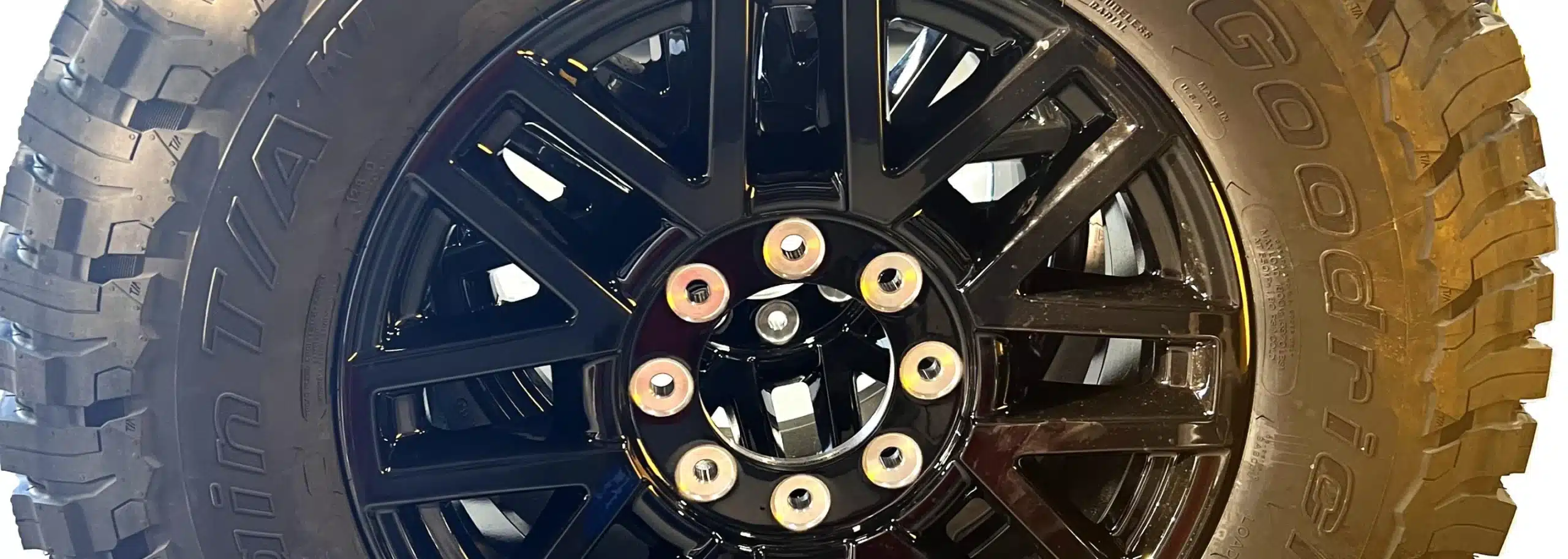 Close-up of a black alloy wheel with a multi-spoke design, hinting at signs that you need new tires. The tire is partially visible on the right side. The image has giving it a monochromatic appearance perfect for tire services in St. Cloud, FL.